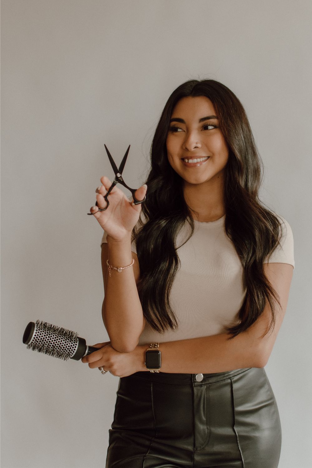 Portrait of Jade, Blondie Hair Salon FL color and cutting stylist, holding shears and a round brush